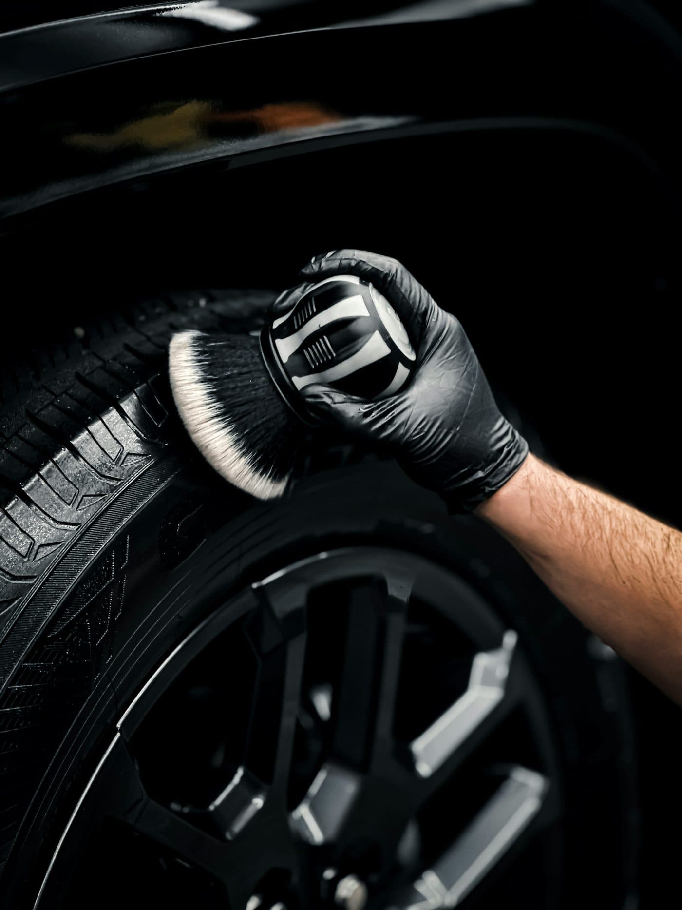 Wheel and tire being cleaned with a detailing brush